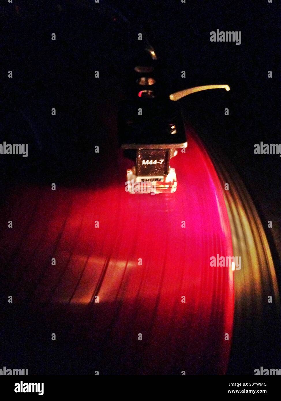Red Vinyl playing on Technics SL1200 turntable with Shure M44-7a cartridge. Stock Photo