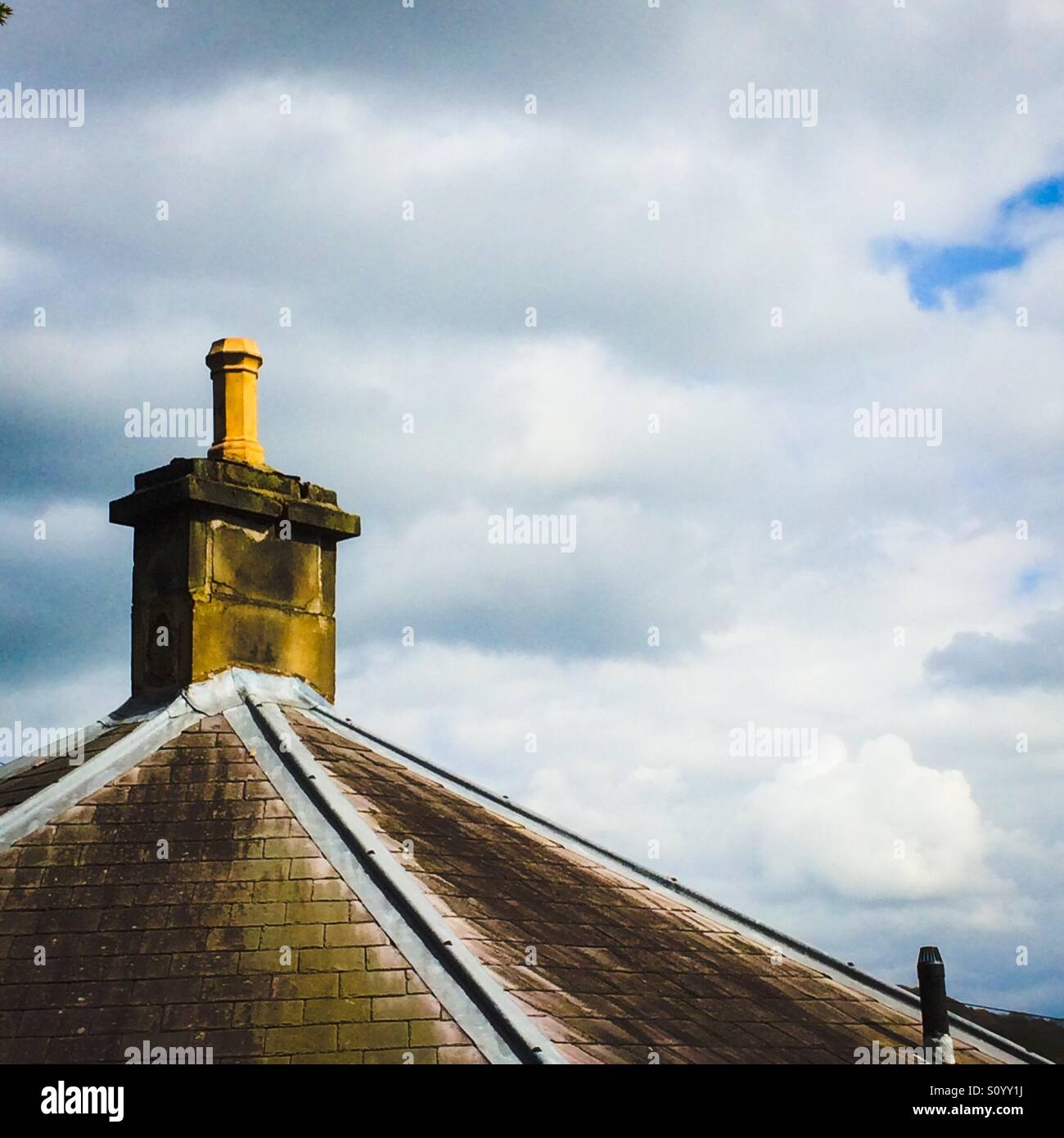 Chimney on roof of house with sky behind - Smartphone Captured Stock Image
