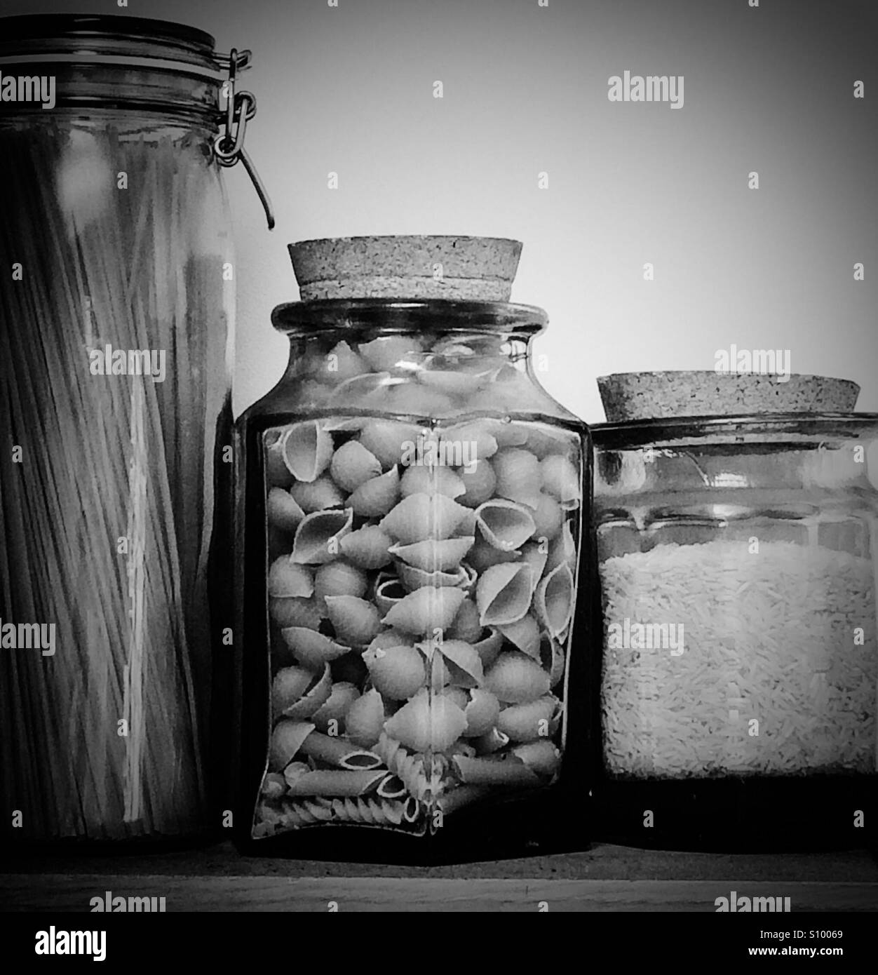 Glass jars containing spaghetti, rice and pasta on a kitchen shelf - Smartphone Captured Stock Image