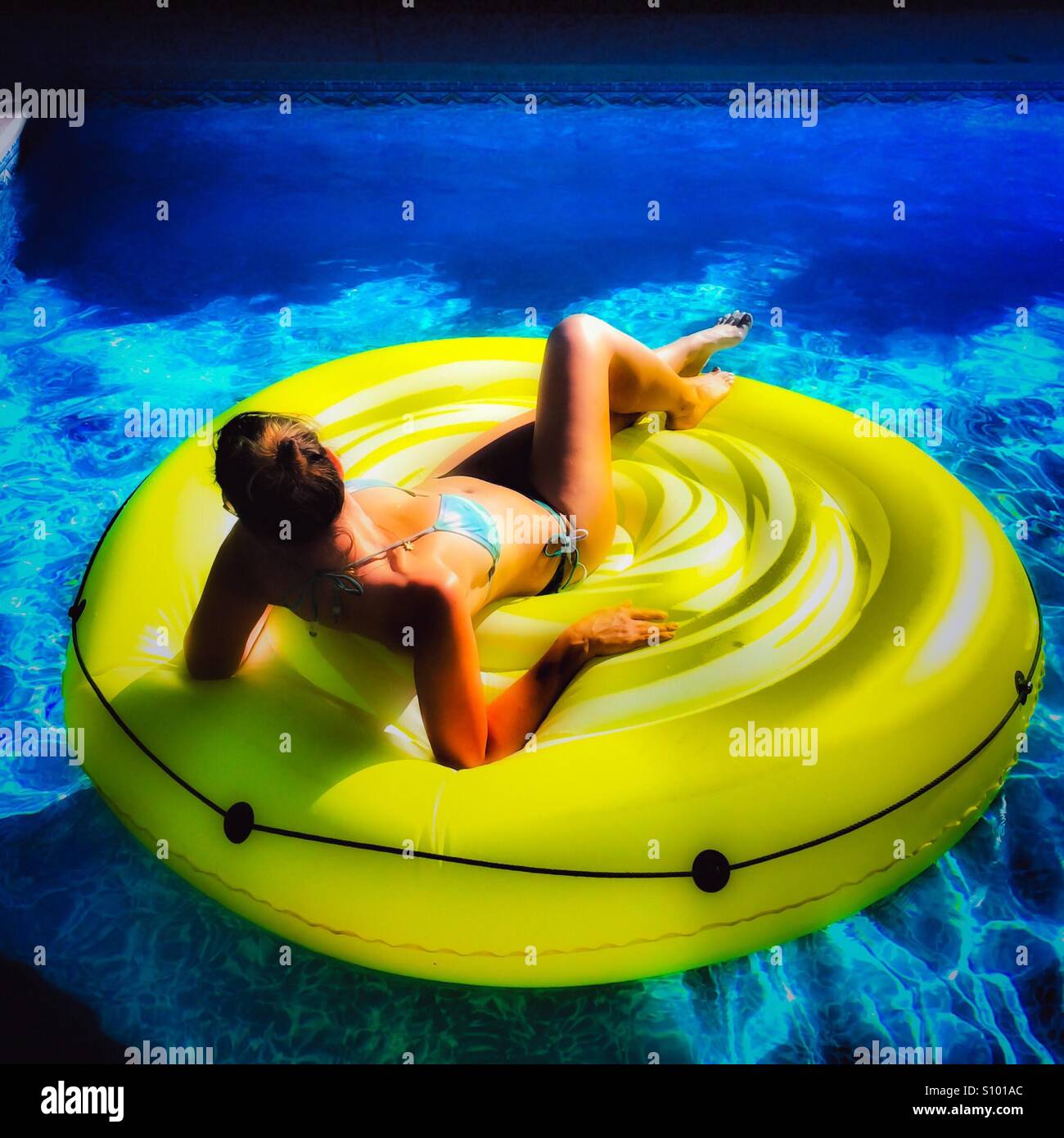Woman relaxing on an inflatable pool toy on a sunny hot day. Square crop. Natural light. - Smartphone Captured Stock Image