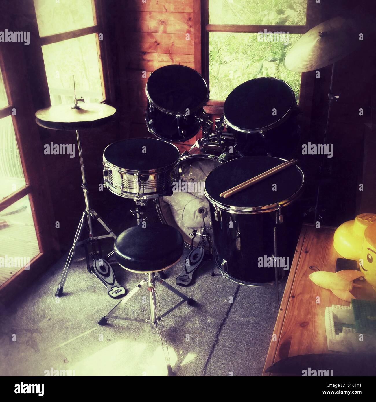Drum set in a cozy wooden summerhouse  with natural light filtering through windows - Smartphone Captured Stock Image
