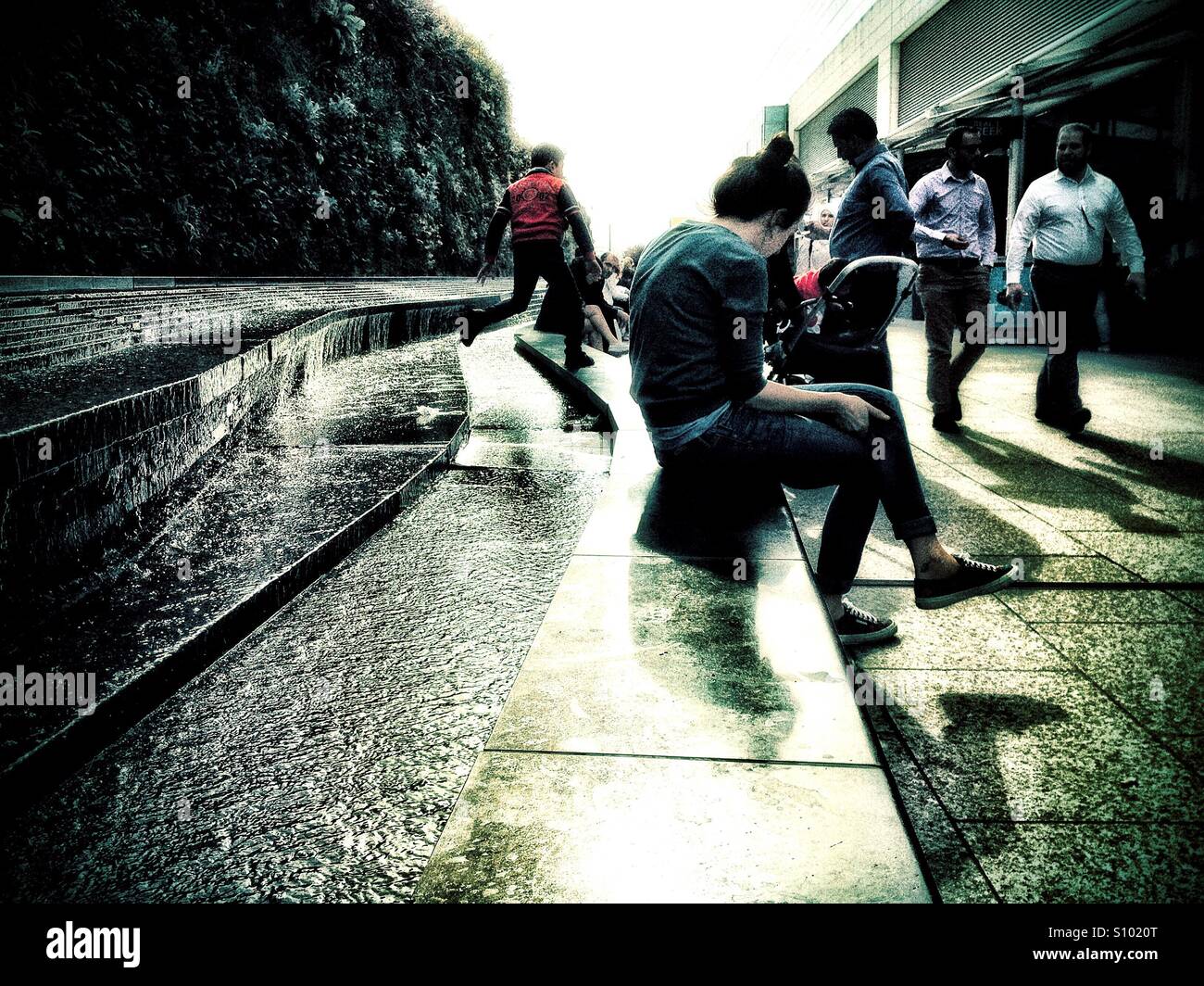 Sitting on the edge of a water feature in a shopping centre. - Smartphone Captured Stock Image