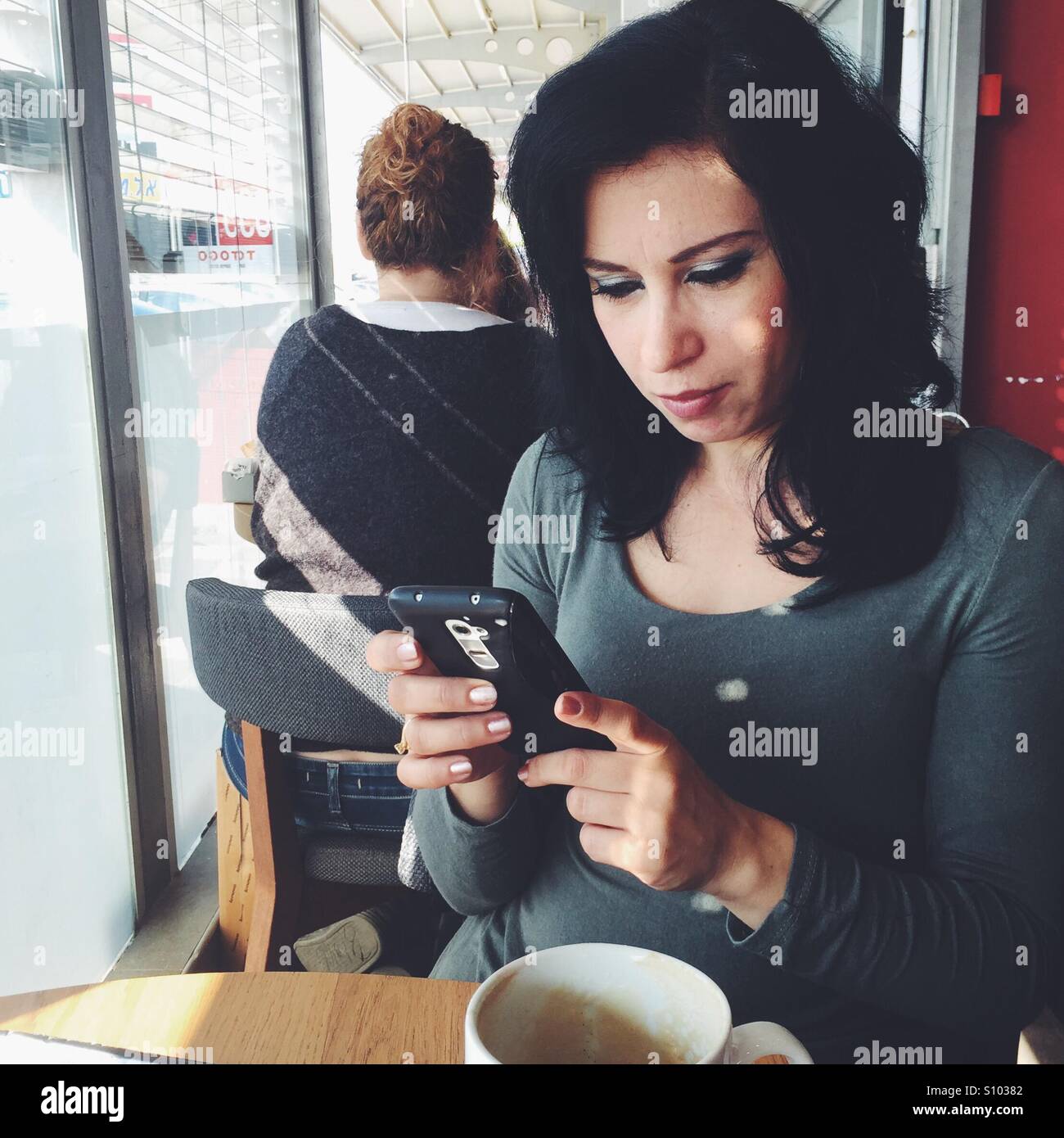 Women using a mobile device. Coffeeshop Stock Photo