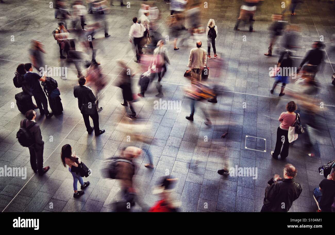Looking down onto a crowded train station with commuters and passengers standing and walking and waiting for their train. Stock Photo