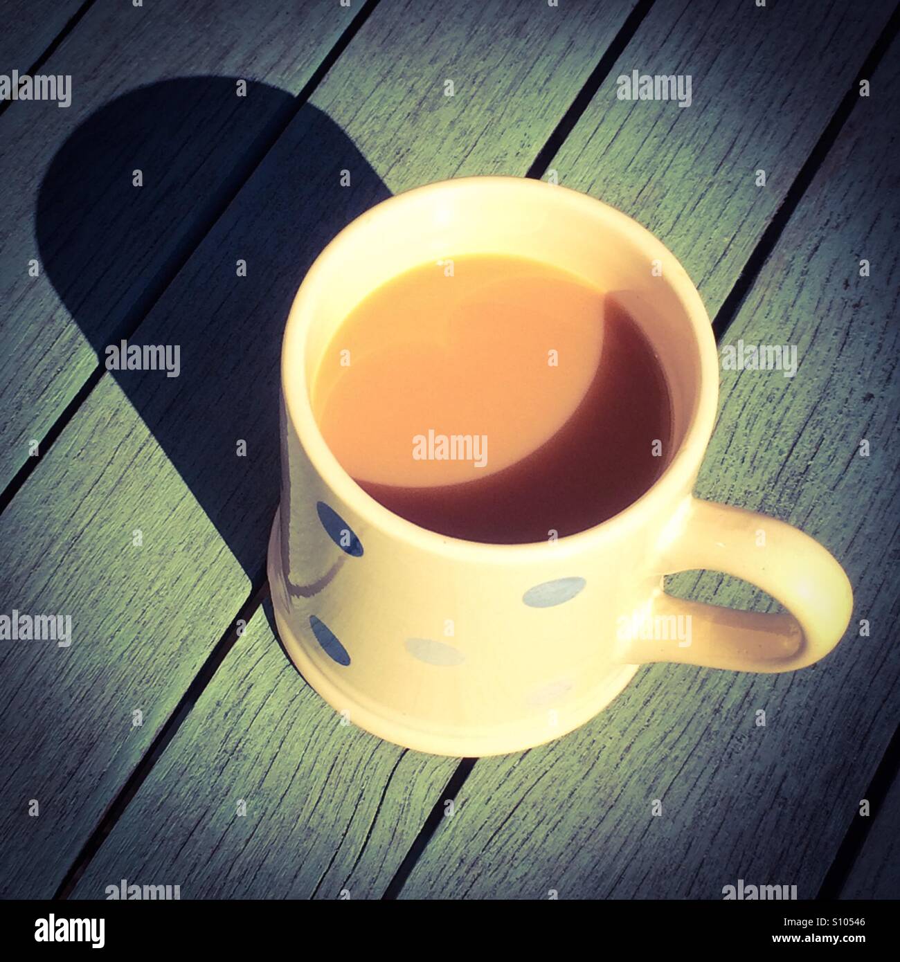 View looking down on a cup of tea on a wooden table - Smartphone Captured Stock Image