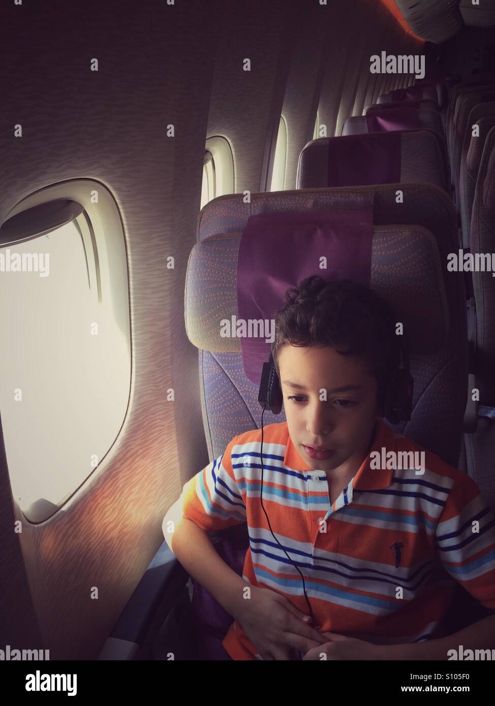 Boy watching movie in Airplane during flight - Smartphone Captured Stock Image