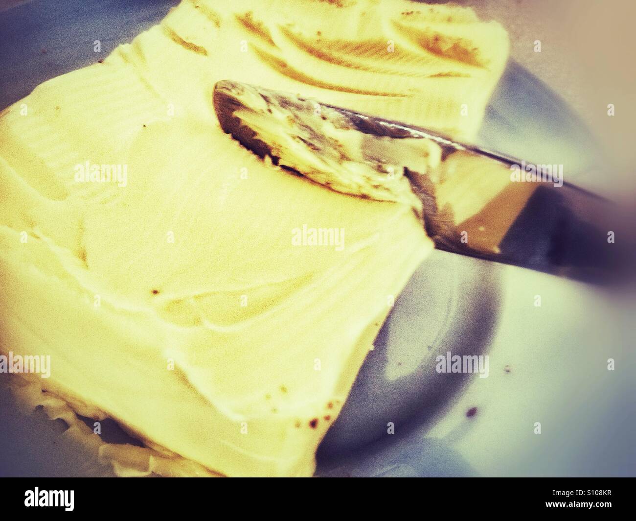A knife cutting through butter. Stock Photo
