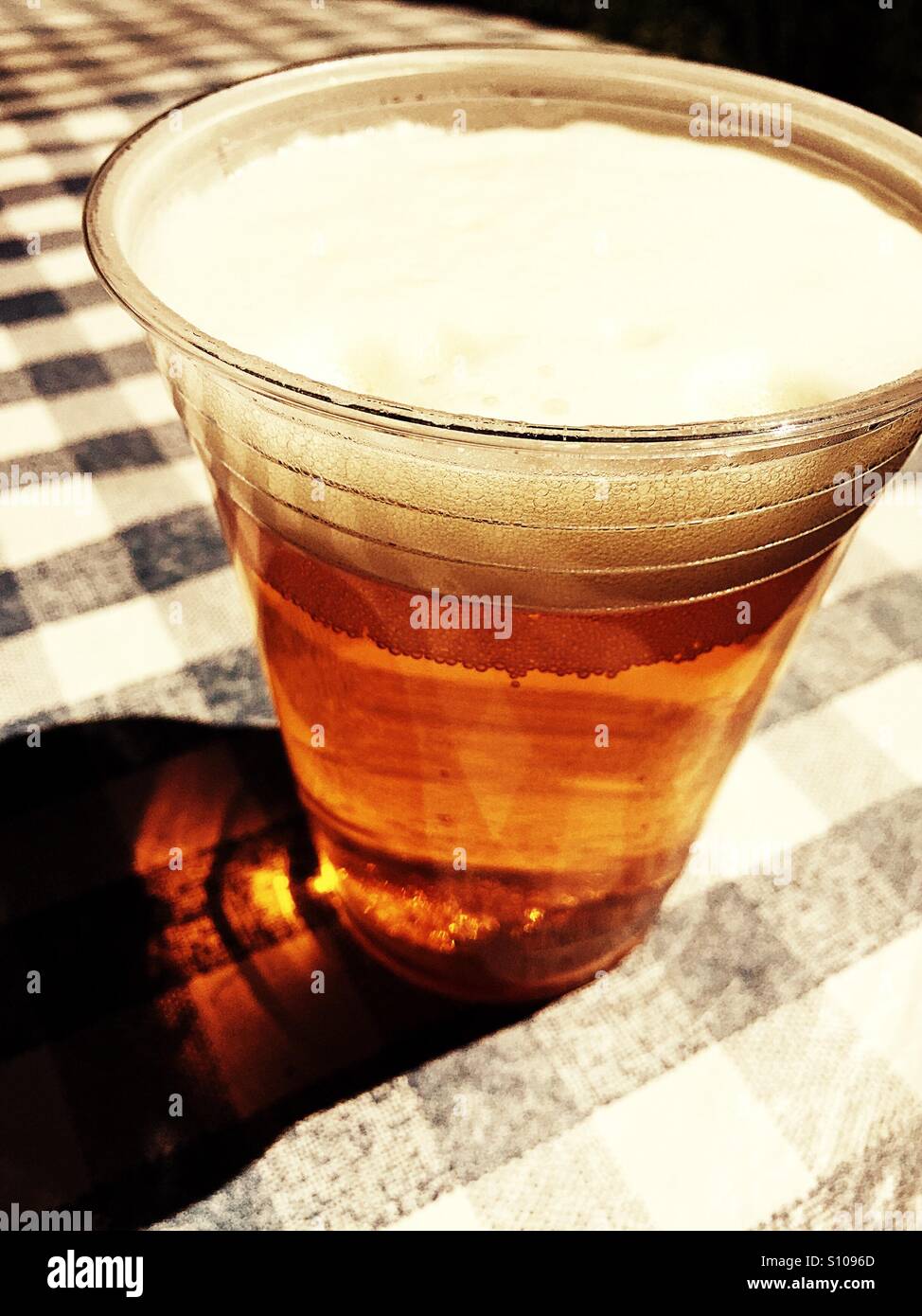 Draft beer in plastic cup on blue and white check tablecloths - Smartphone Captured Stock Image