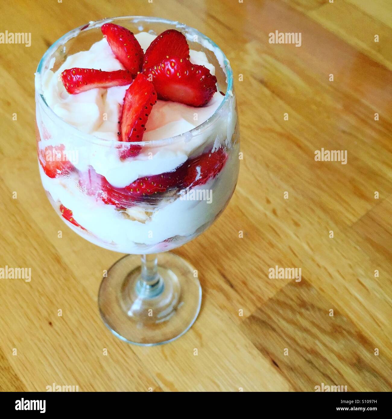 Strawberries with cream dessert in glass on wooden background Stock Photo