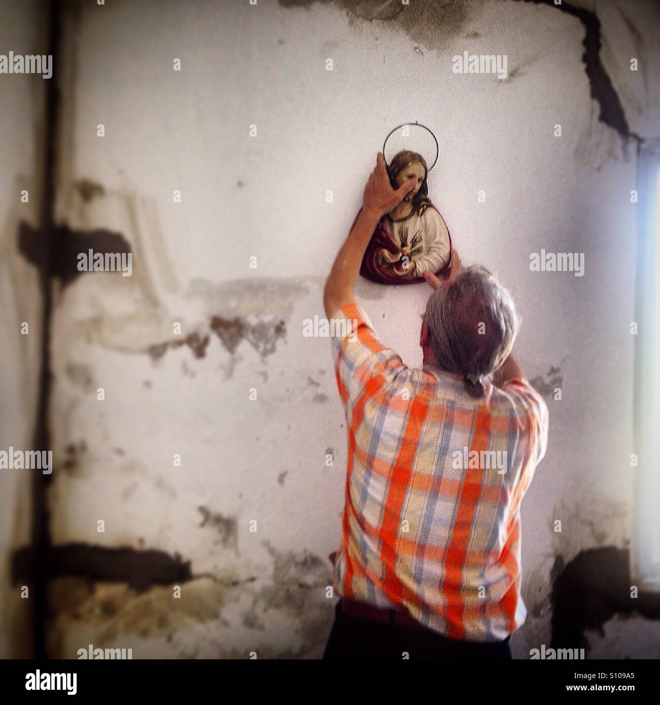 A man holds an image of the Sacred Heart of Jesus in a house under construction in Prado del Rey, Sierra de Cadiz, Andalusia, Spain Stock Photo