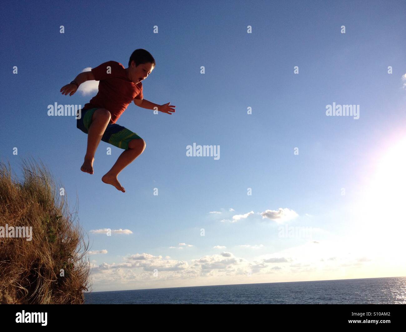 Young boy jumping off sand dunes in France Stock Photo Alamy