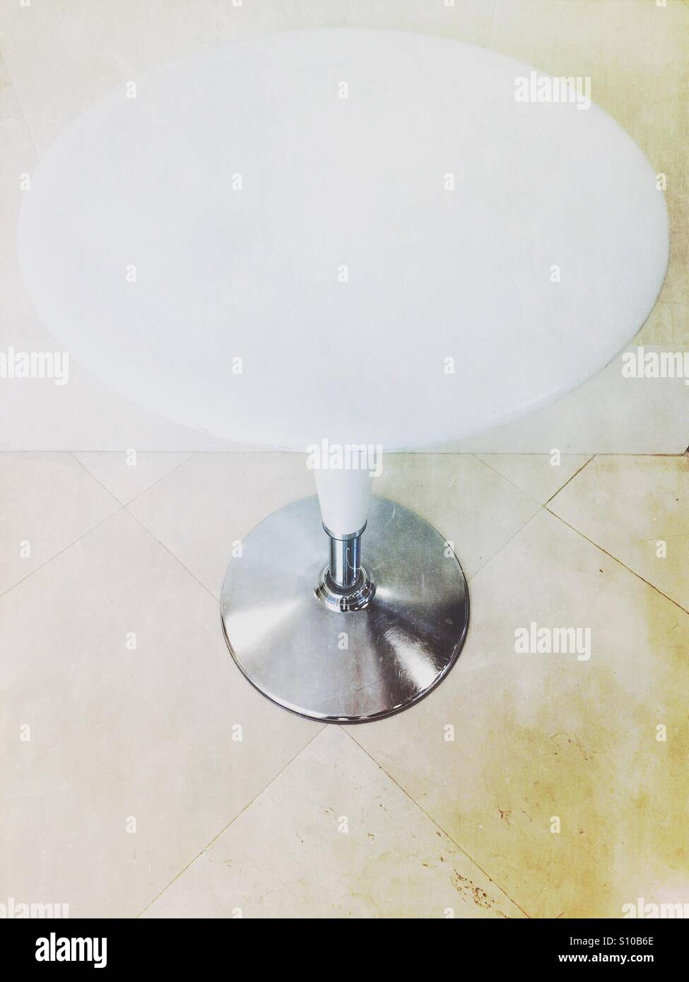 Round empty Bombo table standing on a tiled floor against a wall - Smartphone Captured Stock Image