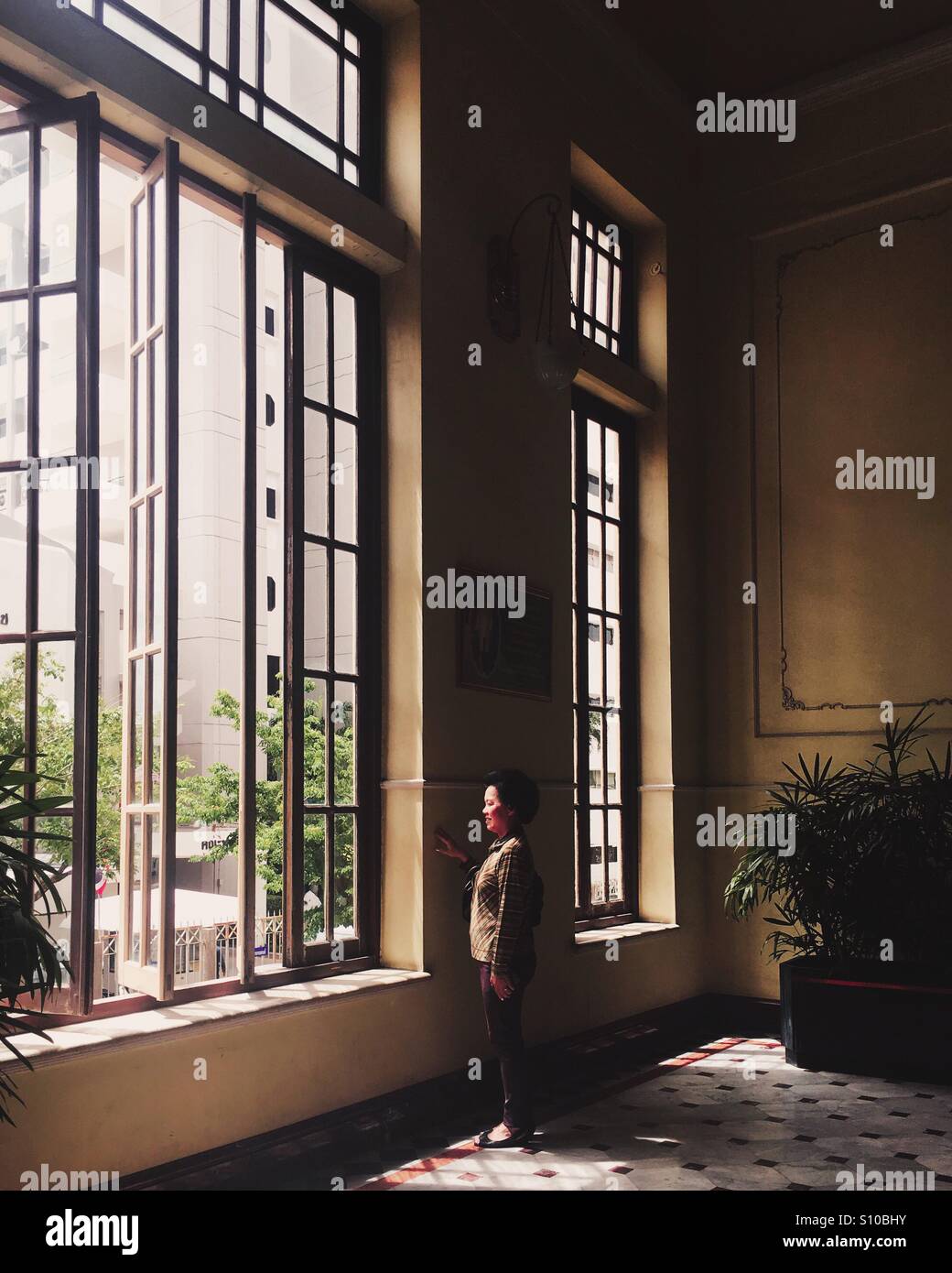 Woman look outside a window Stock Photo - Alamy