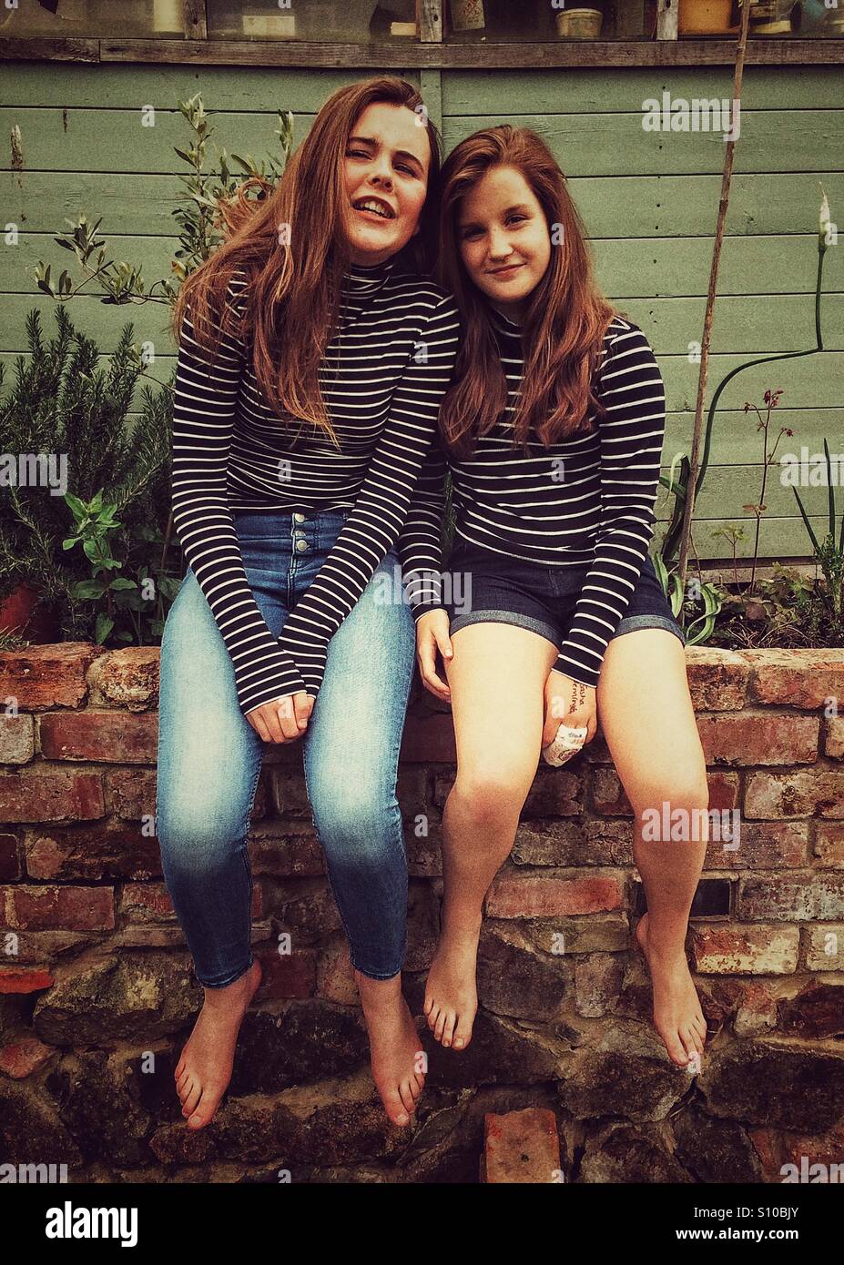 Two girls sitting on a wall - Smartphone Captured Stock Image