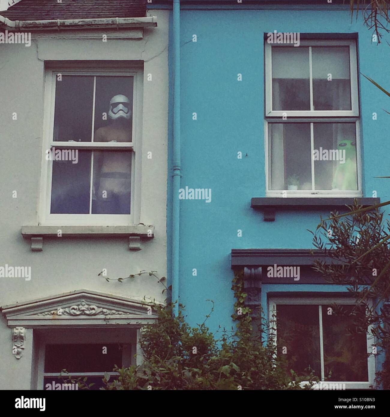 A Star Wars Storm Trooper and an alien look out of the windows of a pair of terraced houses in Falmouth, Cornwall. - Smartphone Captured Stock Image