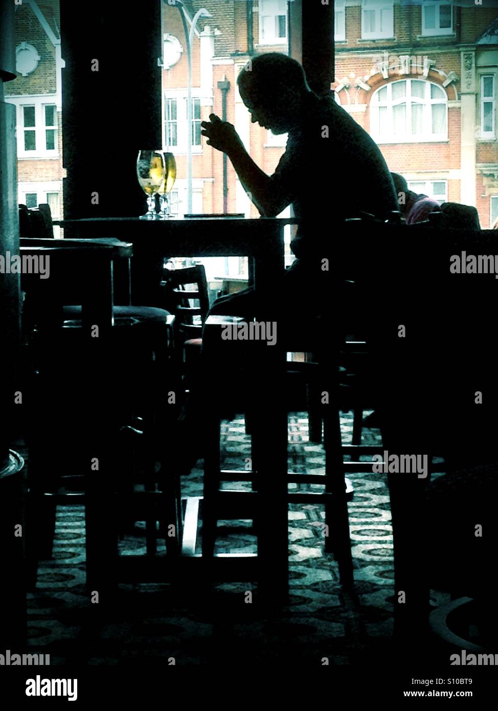 A man sits drinking alone in a bar. - Smartphone Captured Stock Image