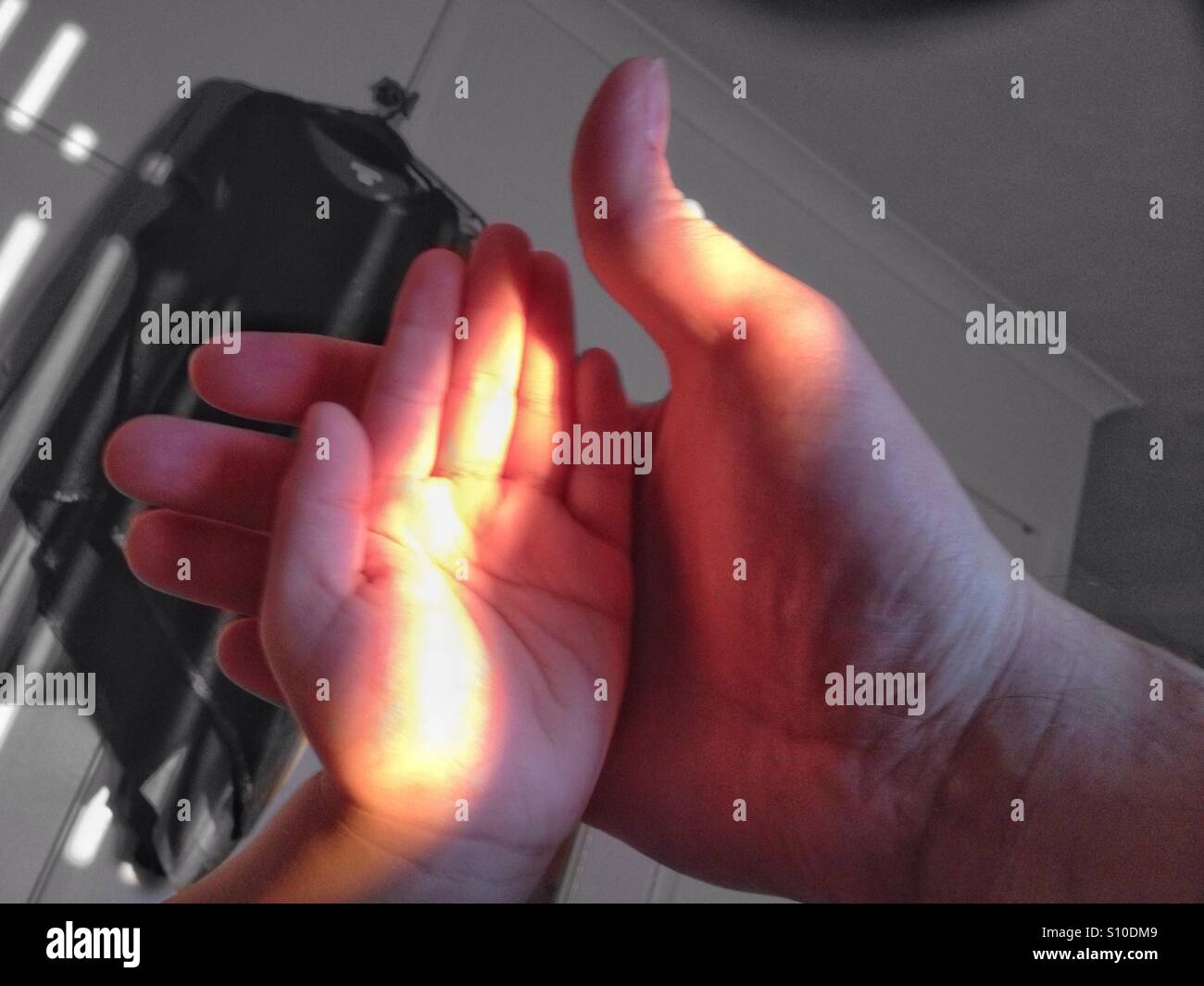 An adult male hand and a young child's hand in a beam of evening sunlight. - Smartphone Captured Stock Image