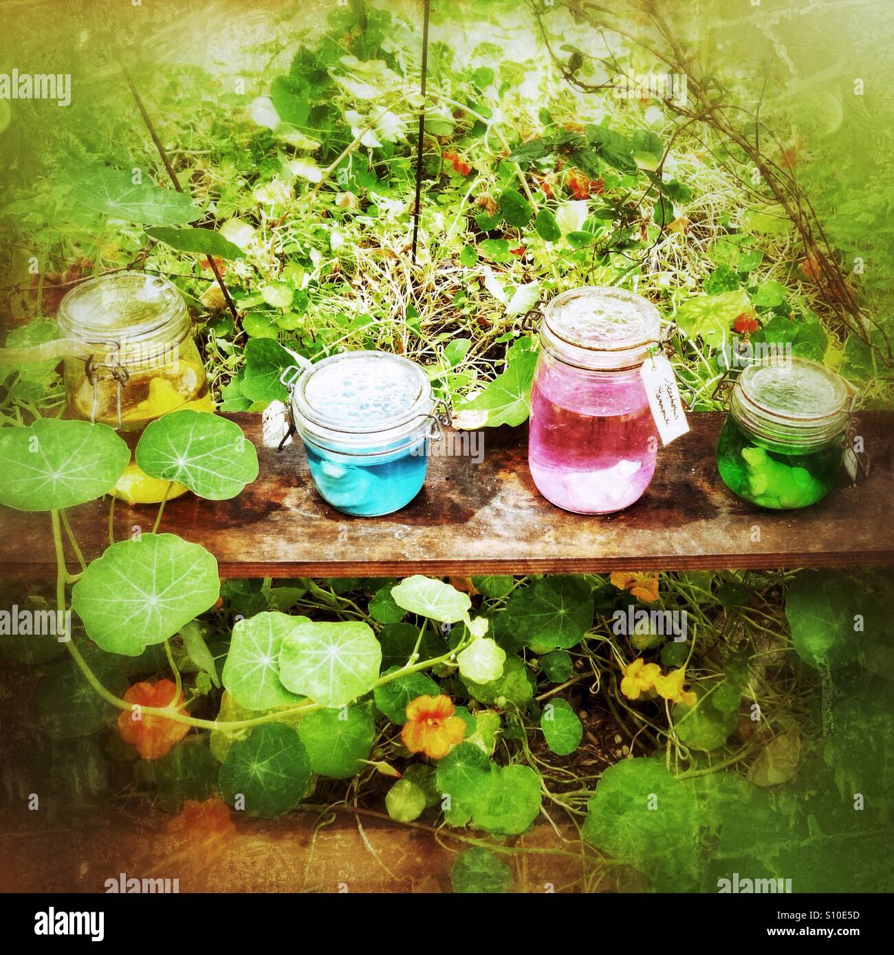 Jars of coloured water in ornamental garden Stock Photo