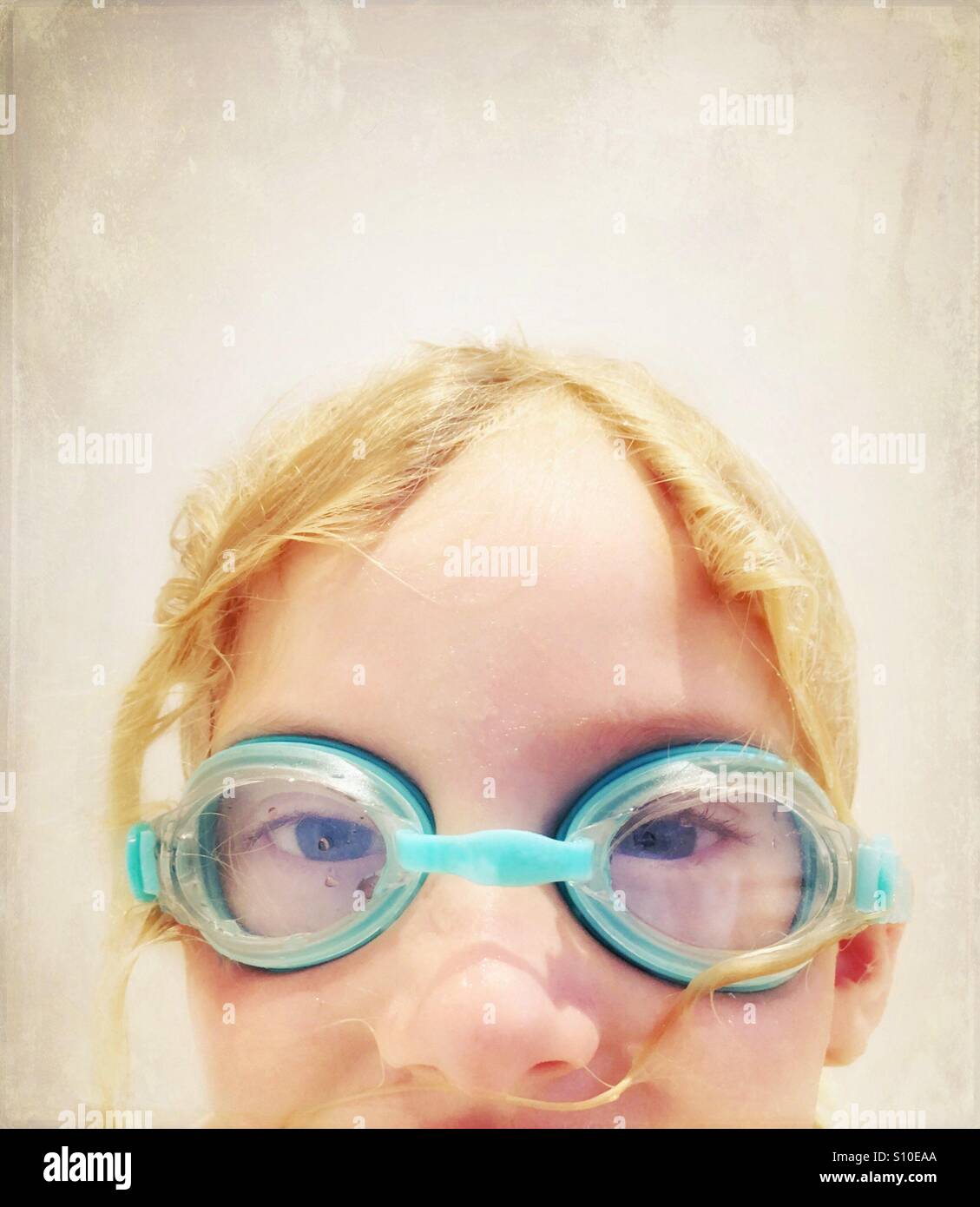 Young girl wearing blue swimming goggles looking directly at camera Stock Photo