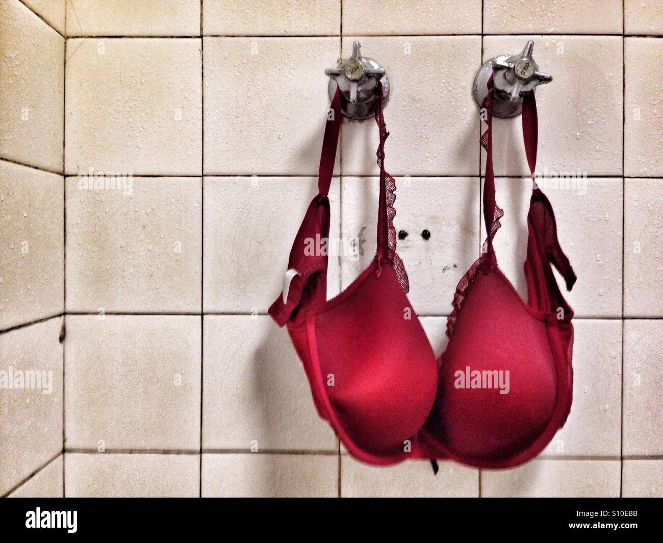 Red bra drying in an old and derelict shower Stock Photo - Alamy
