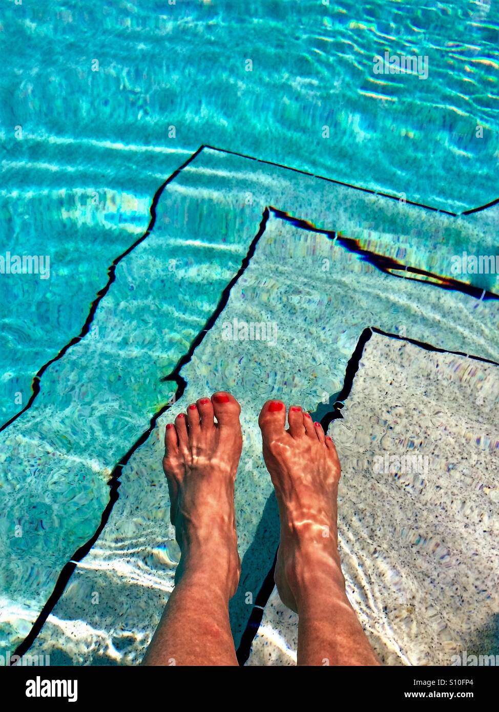 Feet in water with pool steps in background - Smartphone Captured Stock Image