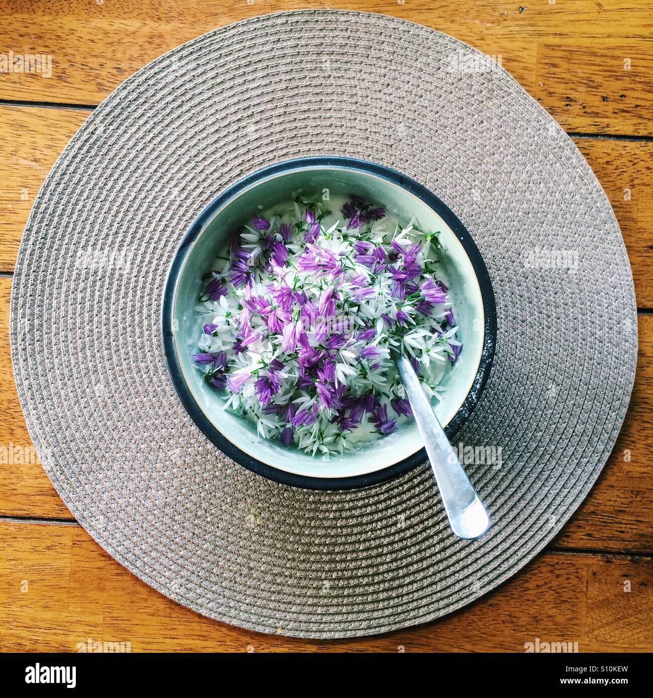Chive flowers and wild garlic flowers in a bowl with ricotta cheese on a wooden table. - Smartphone Captured Stock Image