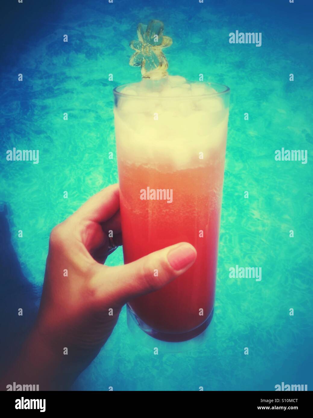 Close up of a woman's hand holding an icy beverage pool side. - Smartphone Captured Stock Image