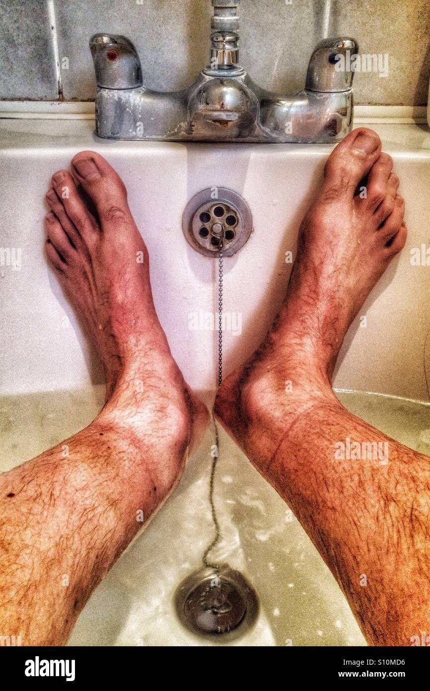 Legs and feet in dirty bath water Stock Photo