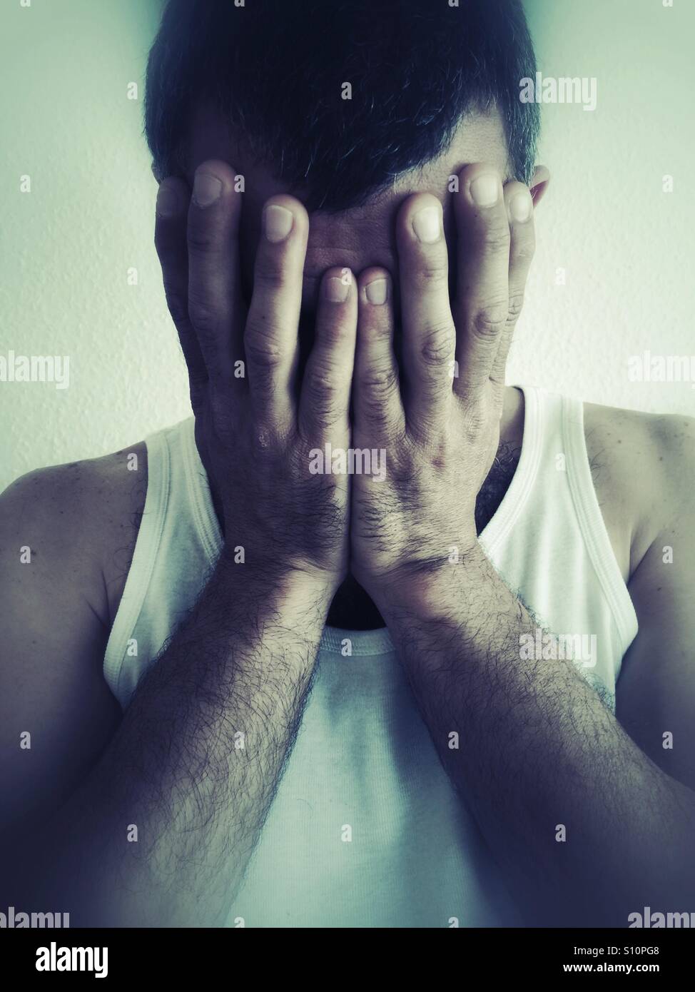 Man hiding his face with his hands Stock Photo