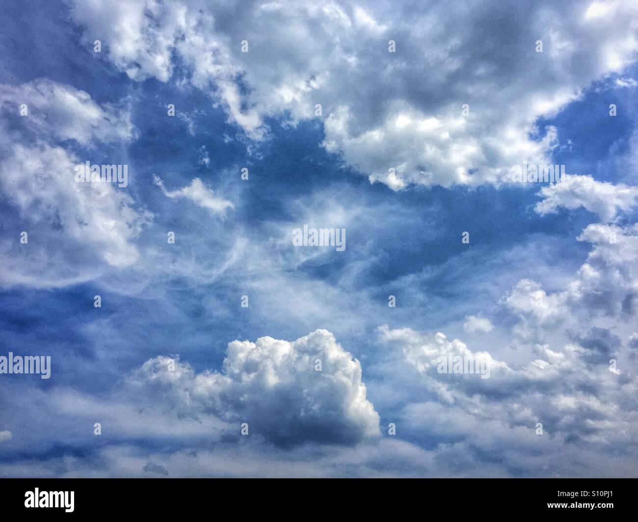 Beautiful fluffy clouds in a see blue sky on a summer day looking like heaven - Smartphone Captured Stock Image