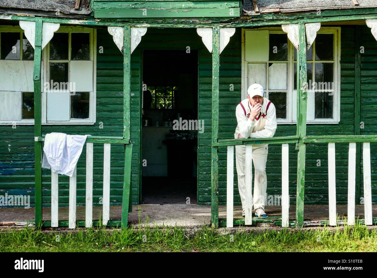 Cricket player smokes outside the cricket club house before the start of play Stock Photo