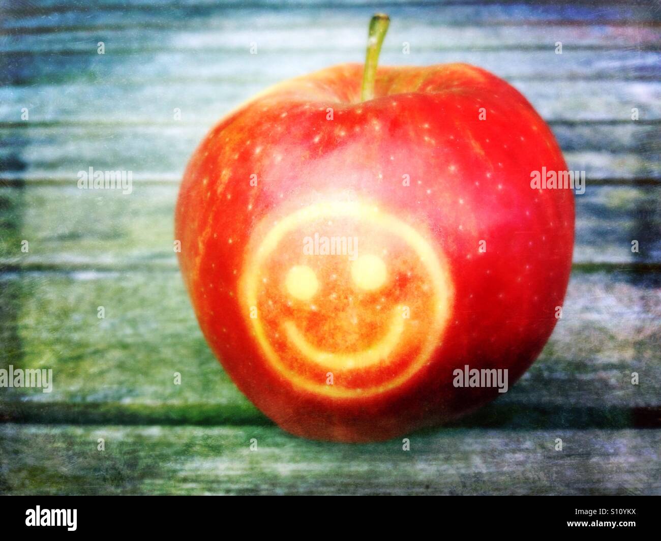 Red apple with smily on wooden table. Stock Photo