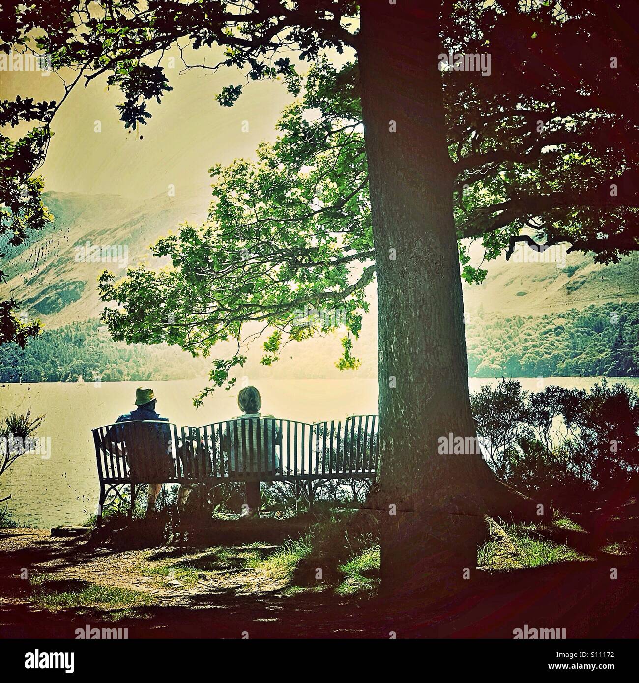 Elderly couple sitting on lakeside bench Stock Photo