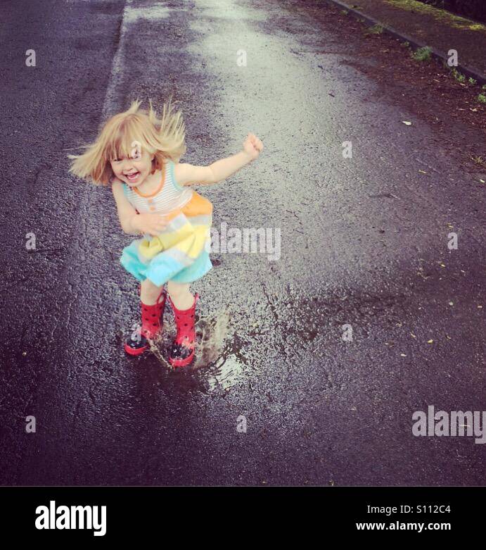 Toddler jumping in puddles Stock Photo Alamy