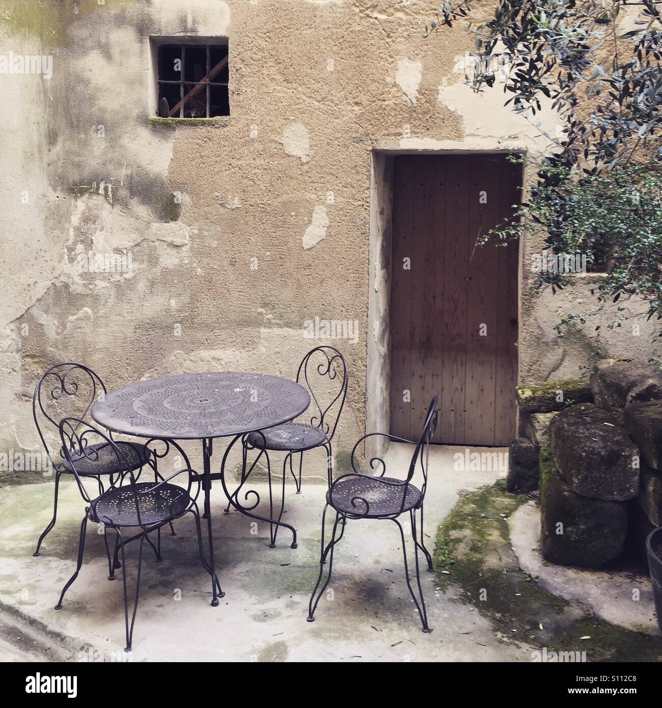 Chair and table in courtyard of a house in Uzes, the Gard, Languedoc Roussillon, France - Smartphone Captured Stock Image