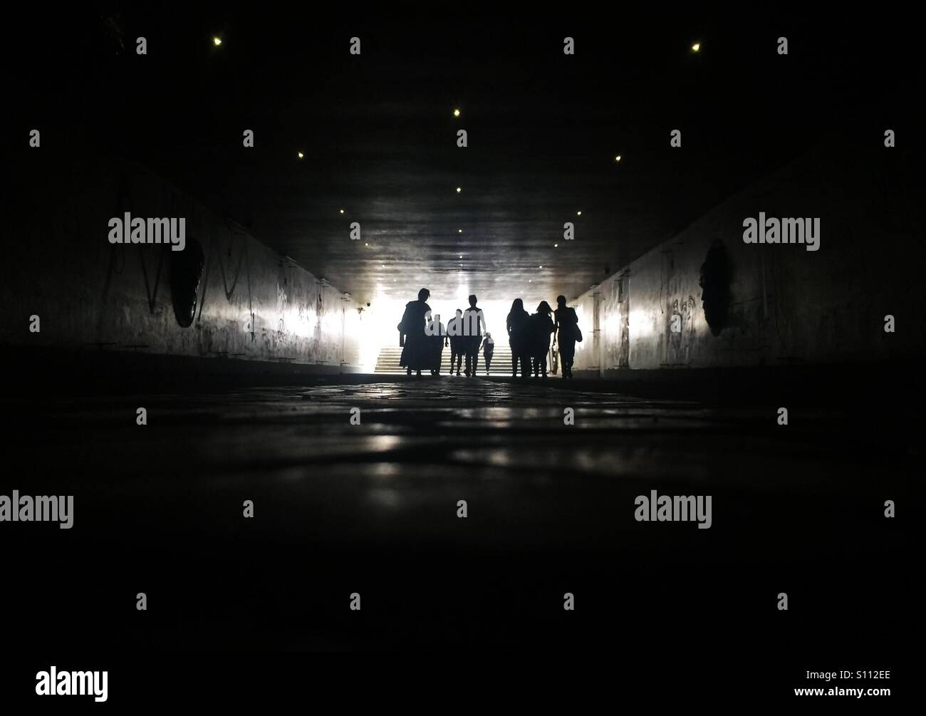 Silhouettes of people walking in pedestrian tunnel - Smartphone Captured Stock Image
