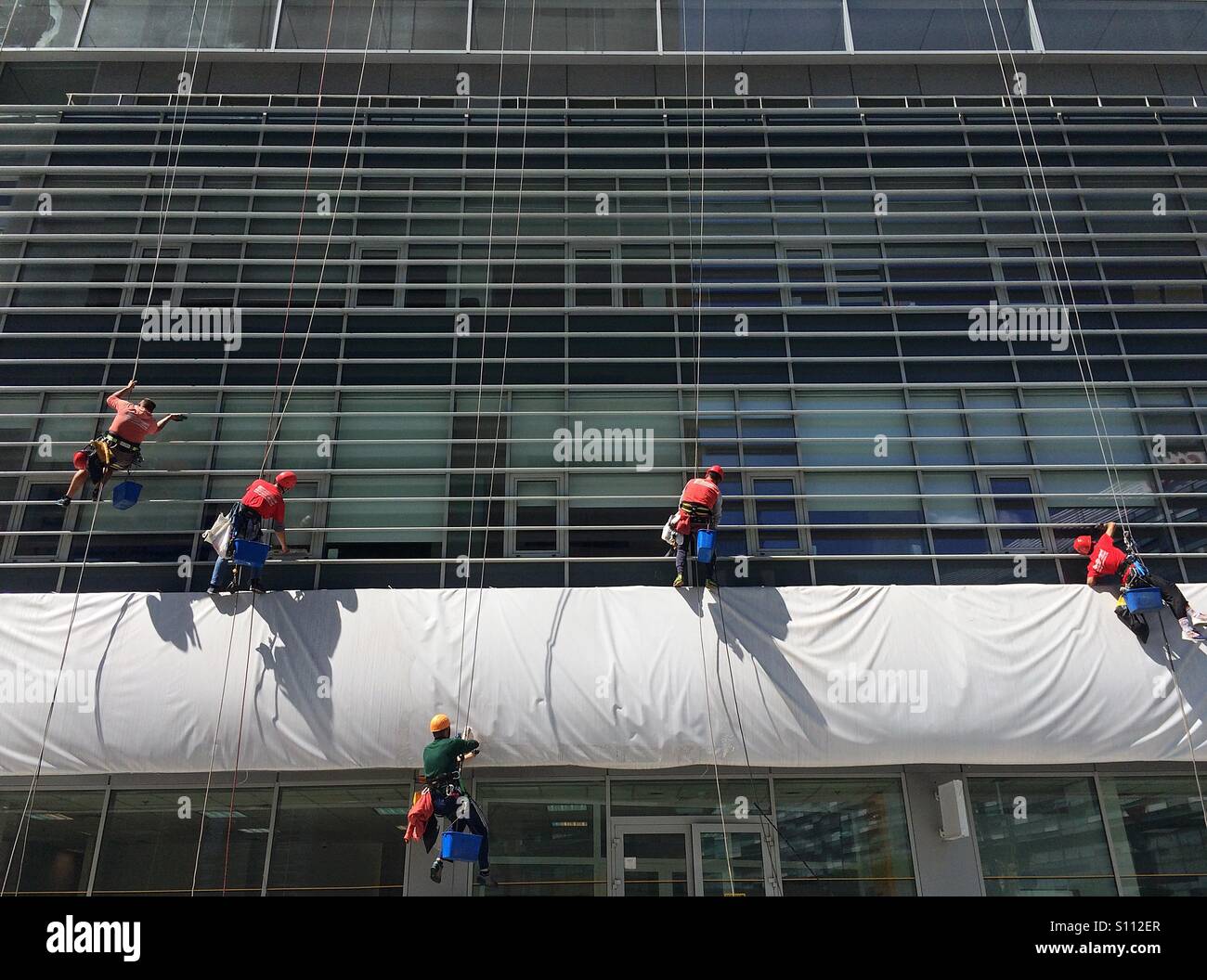 Urban alpinist climbers cleaning office building facade - Smartphone Captured Stock Image