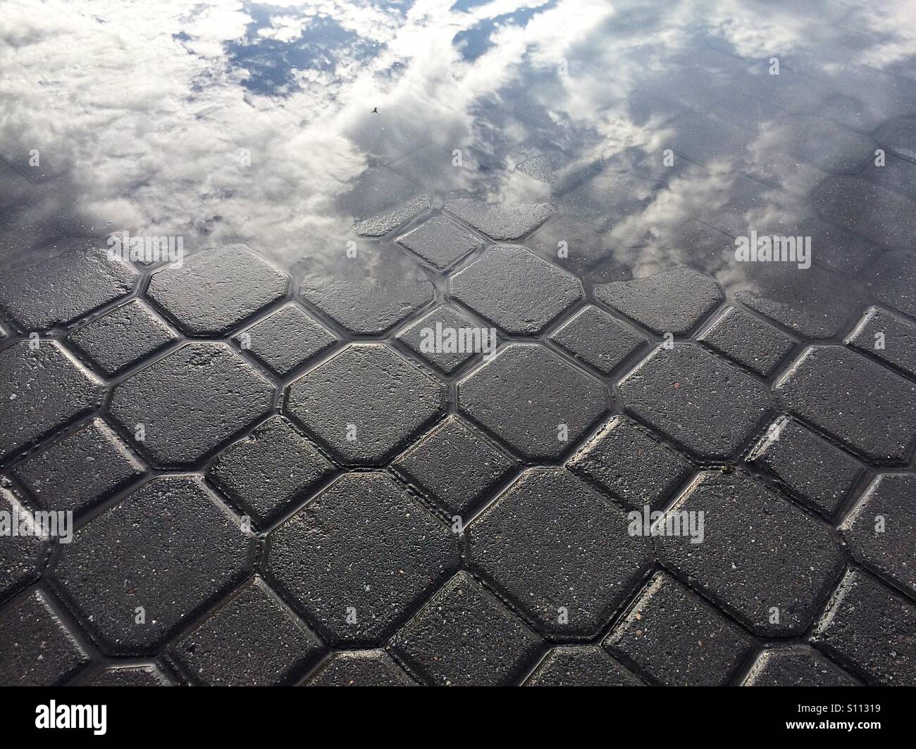 Sky and clouds reflection on wet pavement - Smartphone Captured Stock Image