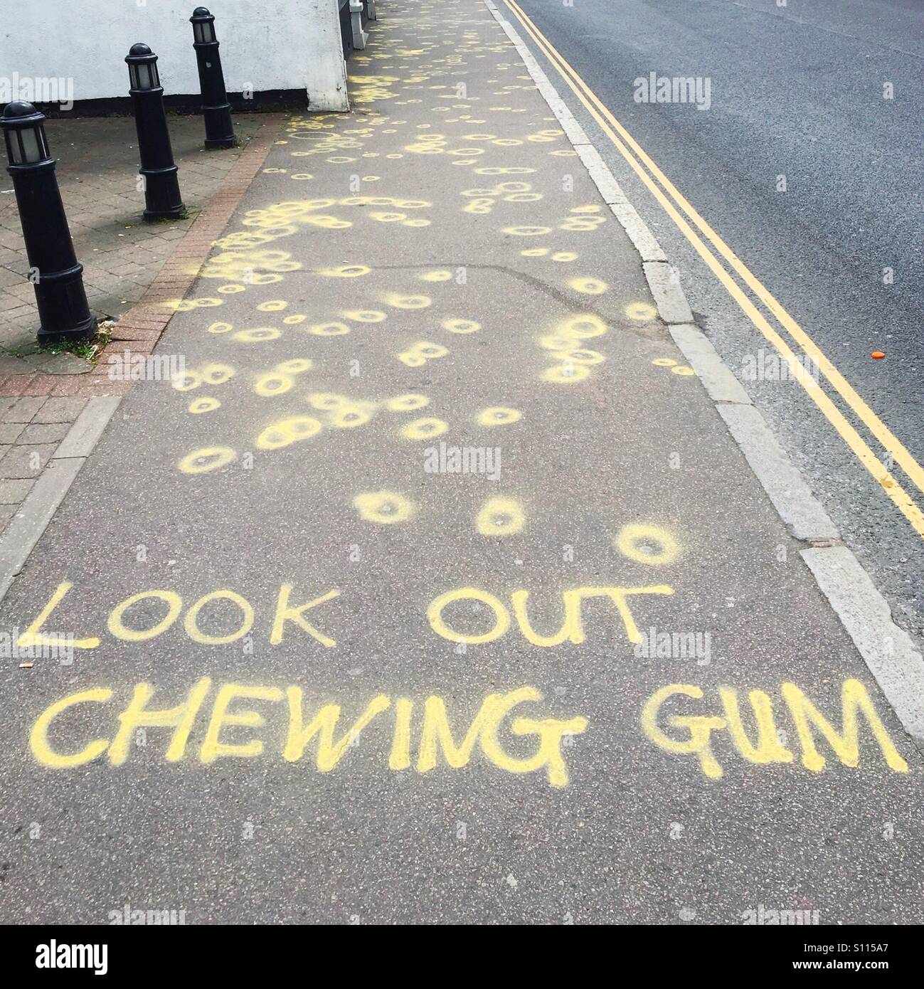 Chewing gum awareness campaign highlighting chewing gum on the floor with the words 'look out chewing gum' sprayed in yellow, by Essex council - Smartphone Captured Stock Image