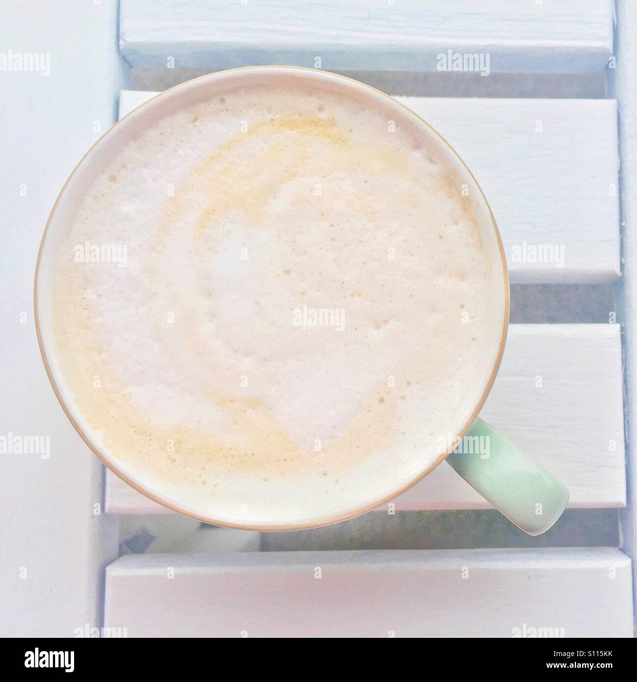 Closeup of a cup of cappuccino from above on an outdoor white table. - Smartphone Captured Stock Image