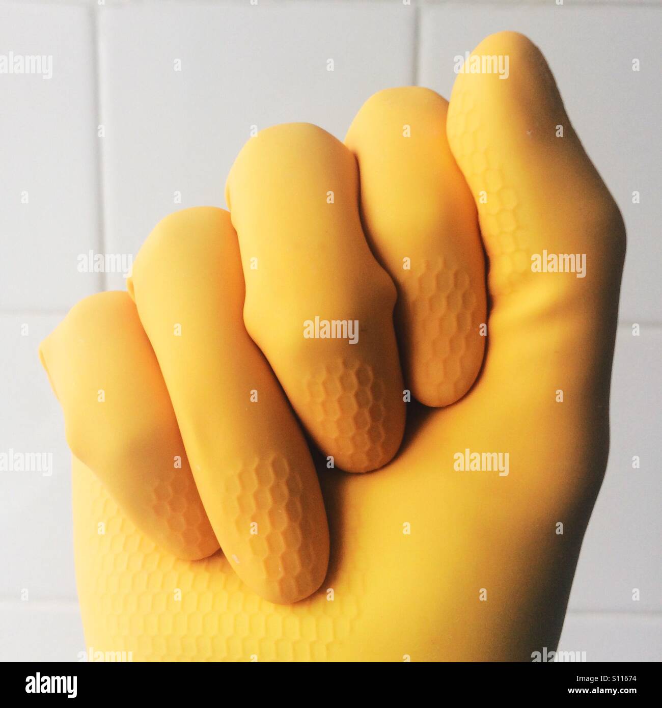 Yellow rubber gloved hand Stock Photo