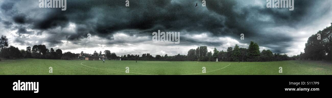 Dark stormy clouds over cricket pitch Stock Photo