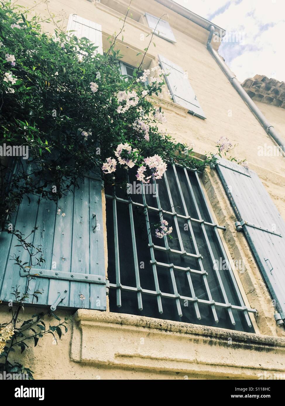 Pretty window with shutters and flowers in a street in the popular town of Uzes, Languedoc, France - Smartphone Captured Stock Image