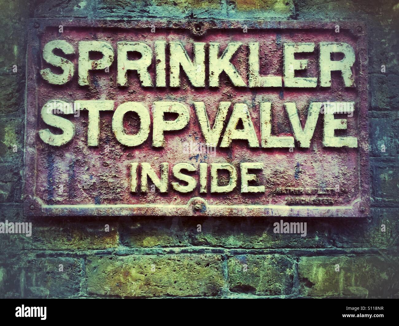Sprinkler stop valve inside sign on brick wall - Smartphone Captured Stock Image