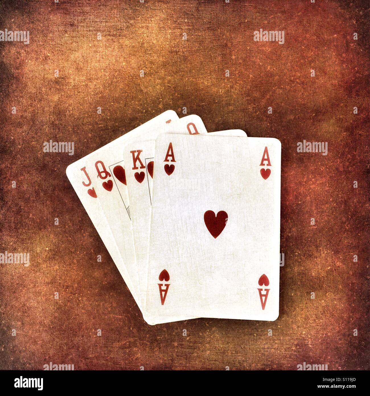 Ace, King, Queen and Jack of Hearts playing cards on a grungy background Stock Photo