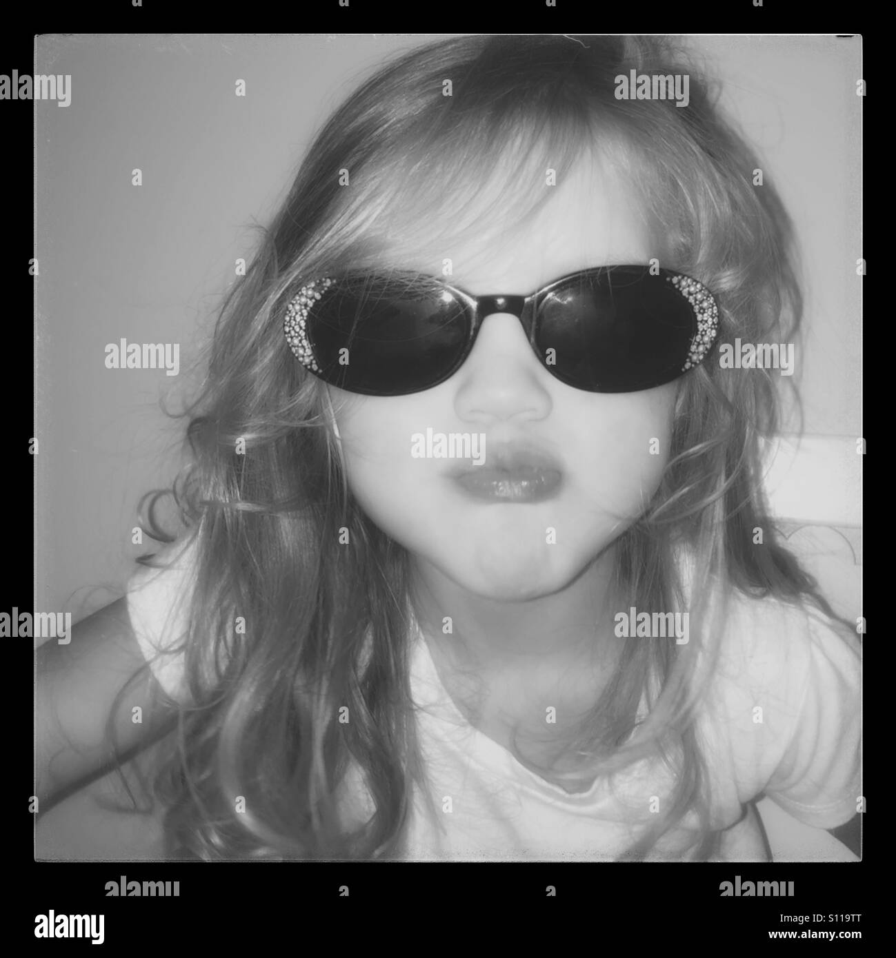 Little girl wearing black sunglasses with rhinestones, making a face Stock Photo