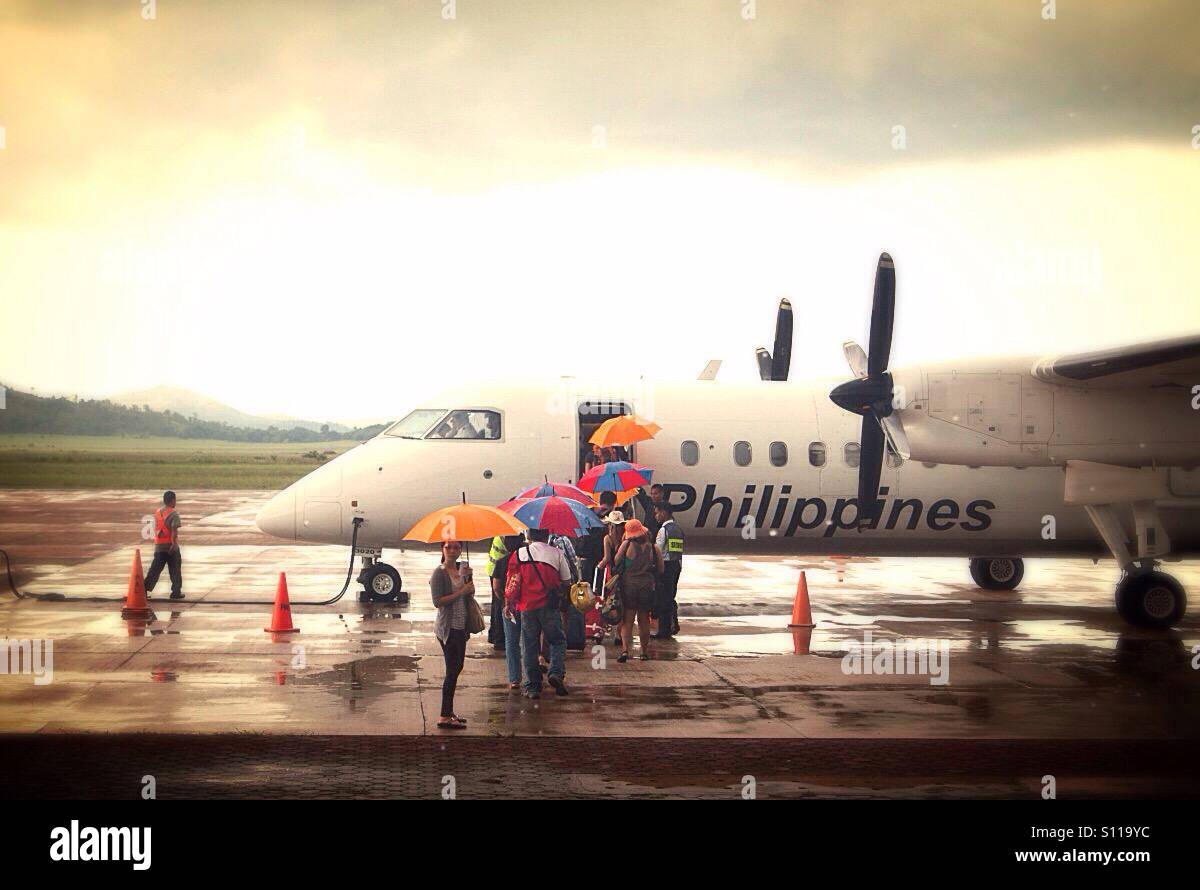 People with umbrellas getting on the plane of Philippines airlines