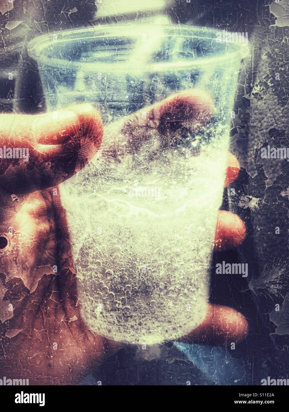 Hand holding plastic cup in which a soluble pain killer has been dissolved. - Smartphone Captured Stock Image