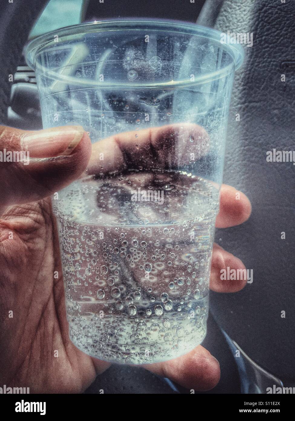 Hand holding a plastic cup of unidentifiable fizzy drink. - Smartphone Captured Stock Image