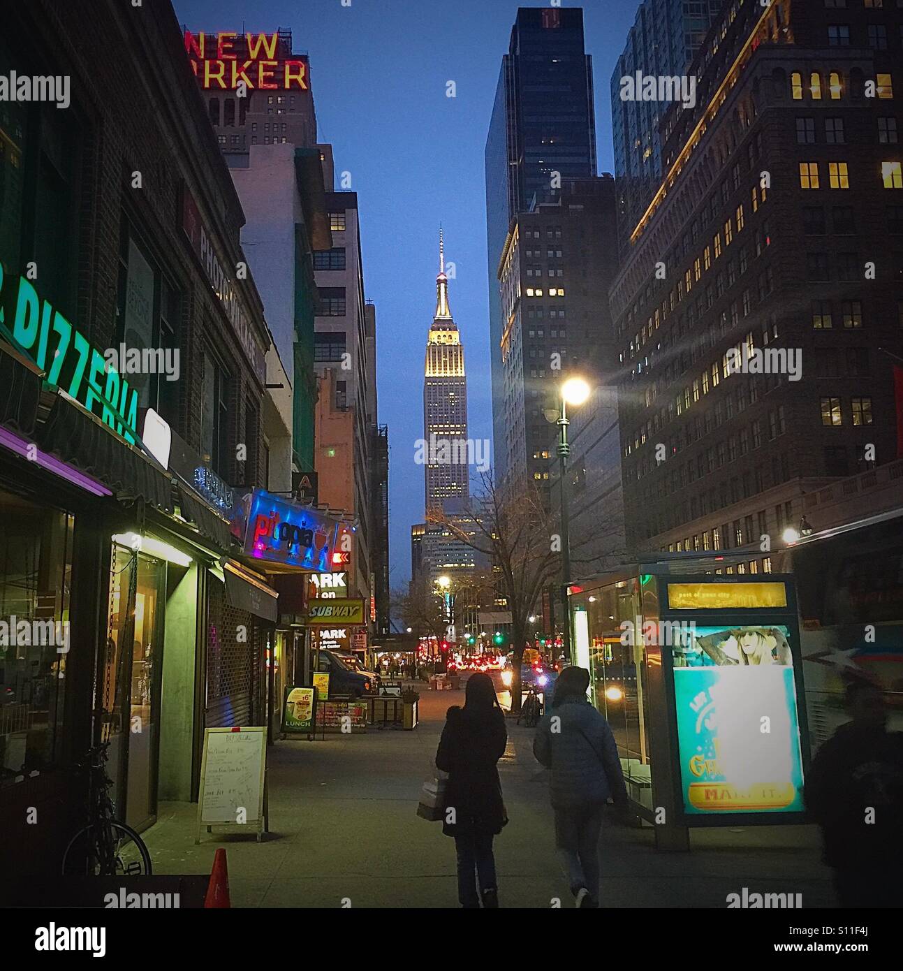 Two people walking towards Empire State Building at twilight. Stock Photo